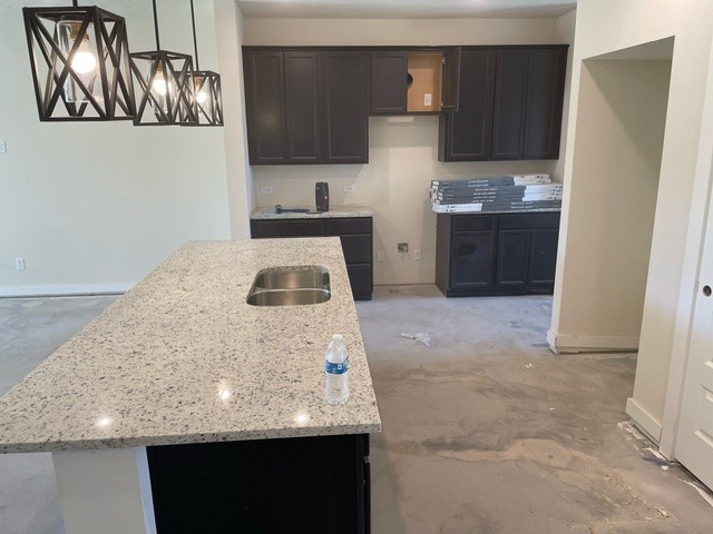 | R&D Marble, Inc. island kitchen with black cabinets and stone countertops