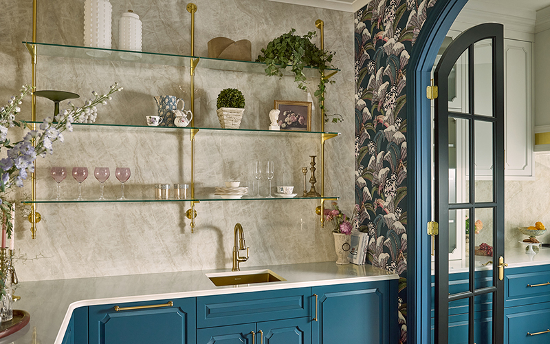 | R&D Marble, Inc. A modern kitchen with a porcelain backsplash that covers the wall with floating shelves of decor and glassware.