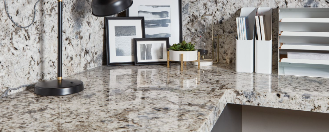 | R&D Marble, Inc. Close up of a kitchen corner granite countertop with backsplash and lamp, books, photo frames and other decor.