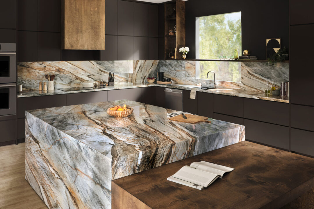 | R&D Marble, Inc. Contemporary kitchen with dark cabinets and dramatic veined marble countertops and island; an open magazine lies on the foreground.