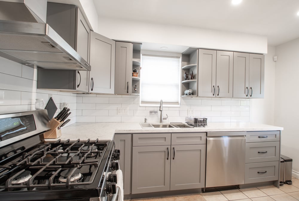 gas stove top and hood fan in a small kitchen with white back splash