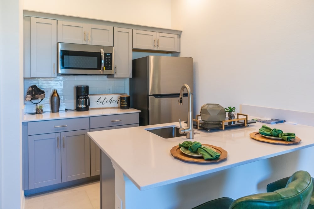 Modern small loft kitchen with refrigerator, sink, microwave with bar stools at counter top