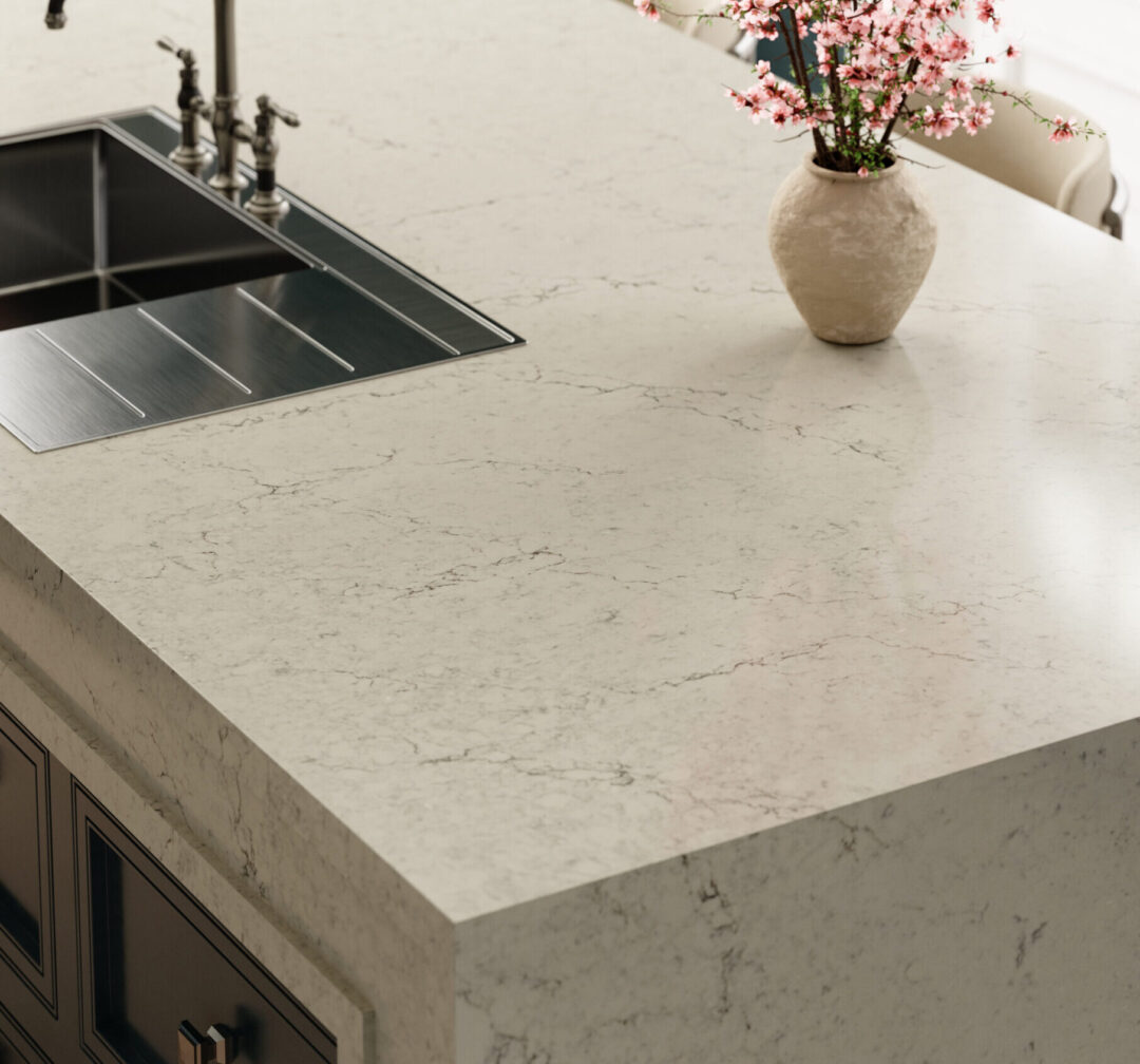 Cambria Windrush Kitchen Rendering by Carter Dodd | R&D Marble, Inc. Marble kitchen island with a dark metal sink and vintage-style faucet, and a beige vase with pink blossoms on the right