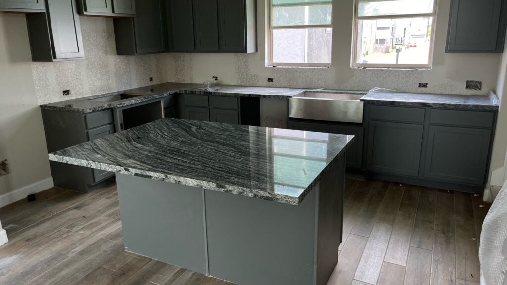 555 | R&D Marble, Inc. Modern kitchen under construction with gray cabinets, speckled granite countertops, and a central island